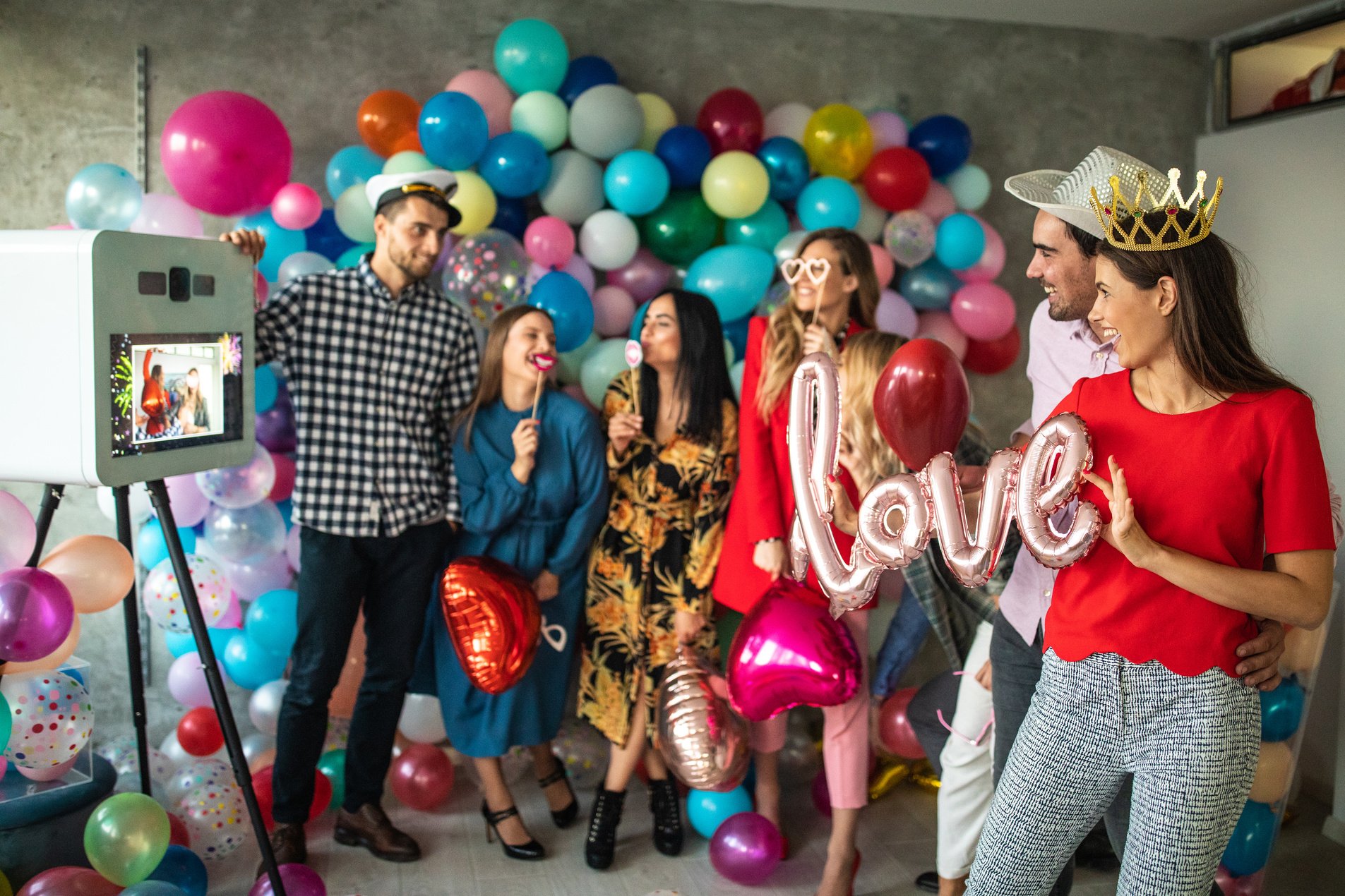 Young couple taking photo using photo booth at party with friends